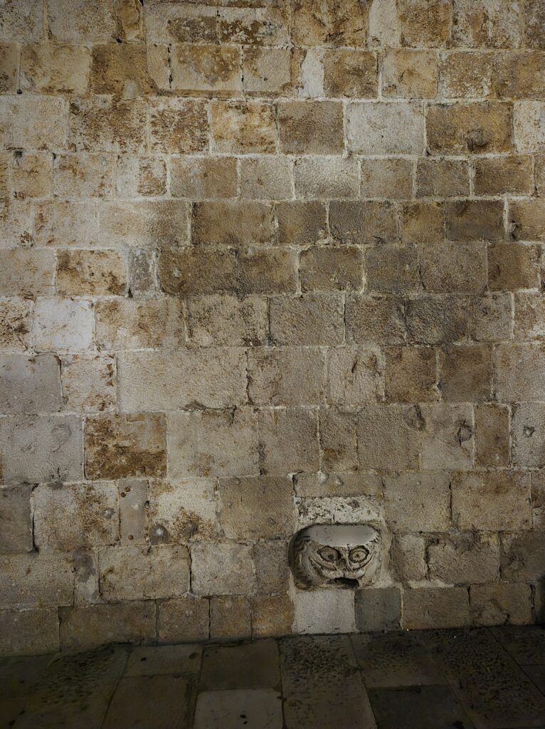 Maskeron gargoyle at the entrance of the Franciscan Monastery in Dubrovnik Old City, designed in a way that makes it difficult for people to stand on it.