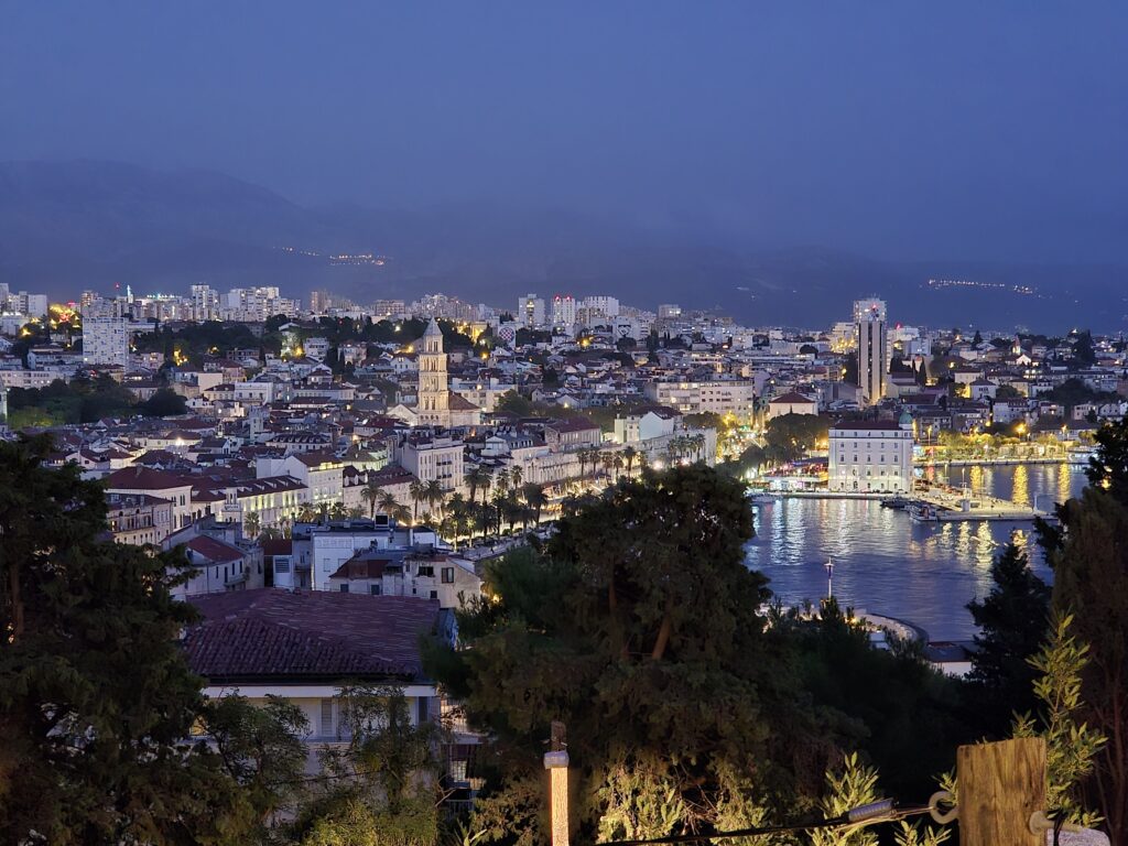 Nighttime view of Split from Spalato viewpoint on Marjan Hill, showcasing the city lights and the Adriatic Sea.