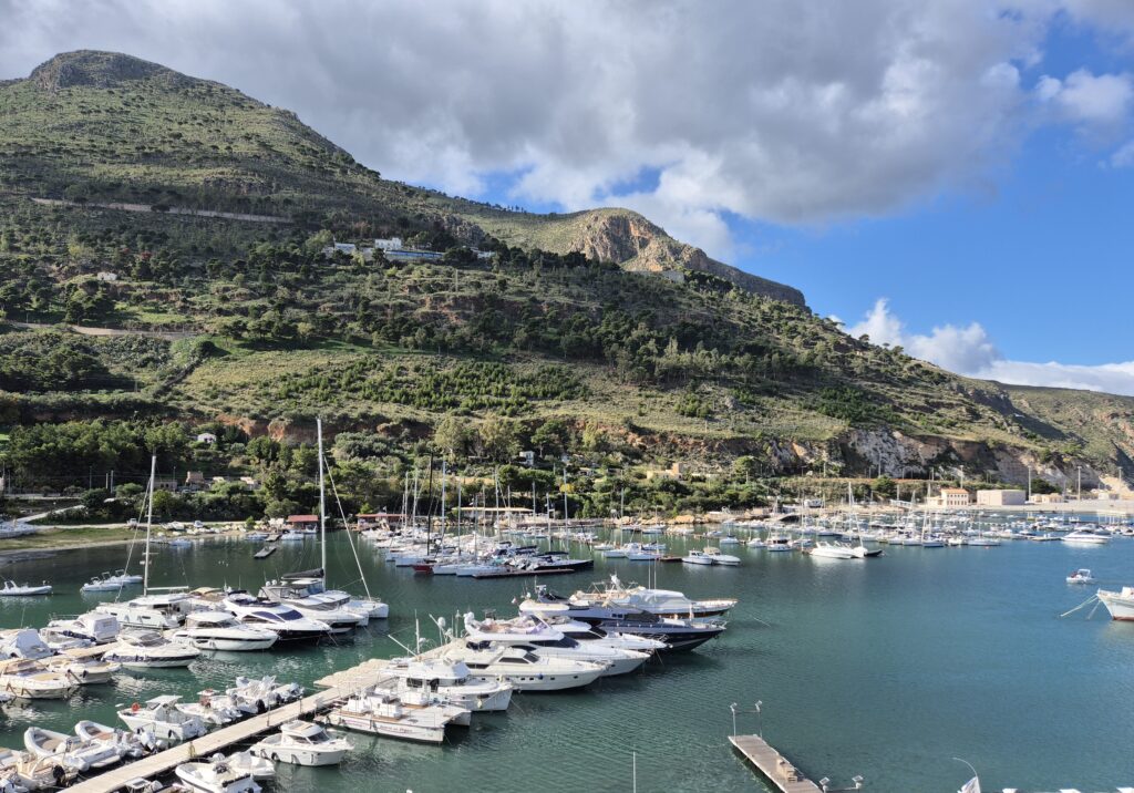 Castellammare del Golfo Townscape: A panoramic view of Castellammare del Golfo, highlighting its charming blend of terracotta rooftops, a bustling harbor, and the dramatic cliffs of Sicily’s stunning coastline.