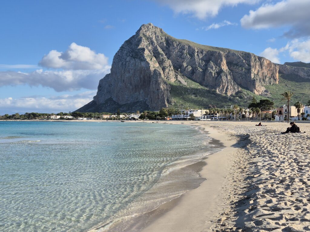 San Vito Lo Capo Beach: A postcard-perfect scene of San Vito Lo Capo beach, often hailed as Sicily’s most beautiful, with soft white sands, calm turquoise waters, and a backdrop of towering cliffs and Mediterranean greenery.