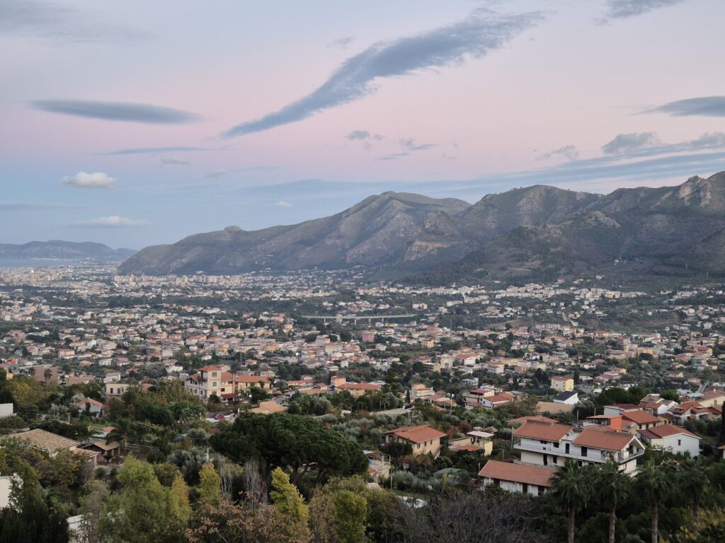 Monreale Panoramic View: A stunning panoramic view from Monreale, overlooking the rolling hills of Sicily, the sprawling Palermo valley, and the shimmering Mediterranean coastline, all bathed in warm, golden light. An ideal spot to experience the natural beauty and tranquility of Sicily.