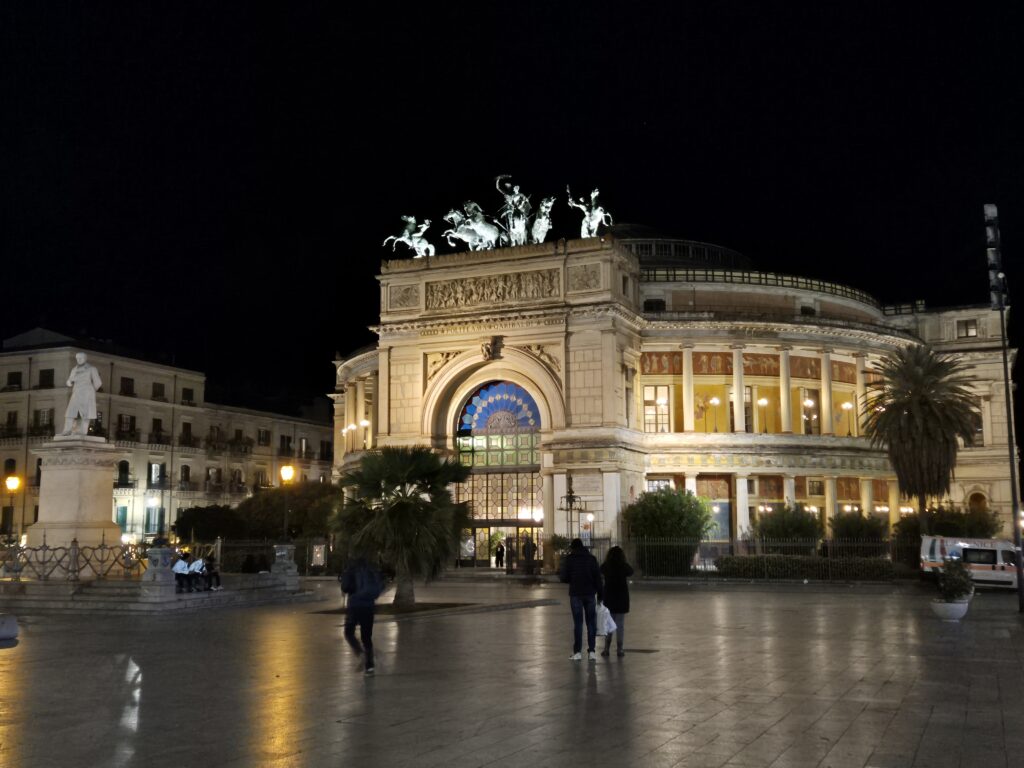 The grand exterior of Teatro Massimo, Palermo's iconic opera house, featuring classical columns and statues, a symbol of the city's rich cultural heritage.